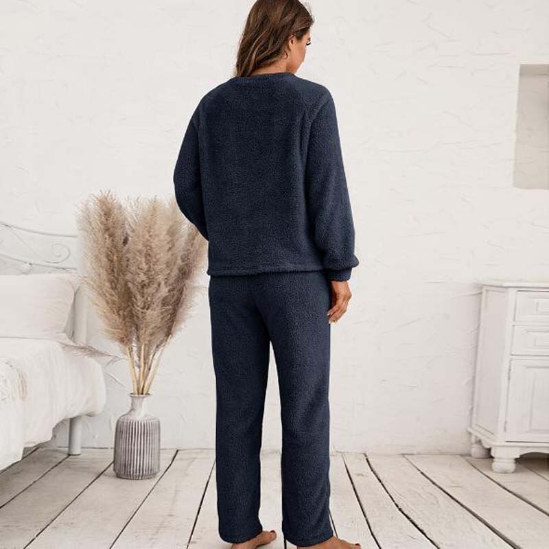 Frau in dunkelblauem Fleece-Pyjama-Set im Schlafzimmer, gemütliche Nachtwäsche.