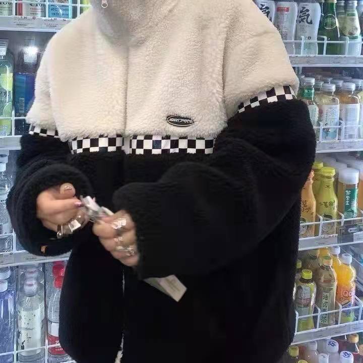 Person in schwarz-weißer Fleecejacke mit Karomuster vor Getränkekühlschrank.