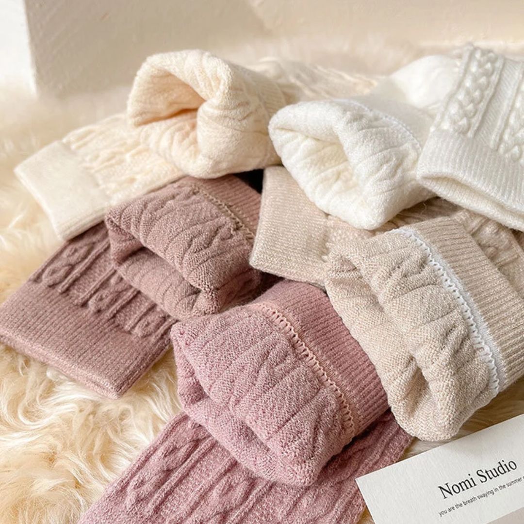 Mehrfarbige Strickstrümpfe aus Wolle, warm und gemütlich, ideal für den Winter, auf Fellunterlage.