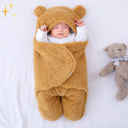 Schlafender Säugling in braunem, flauschigem Babyschlafsack mit Bärenohren, neben Plüschtier.