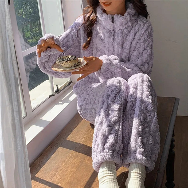 Frau in lila Fleece-Pyjama mit Kapuze, sitzt am Fenster, hält Teller mit Bagel.