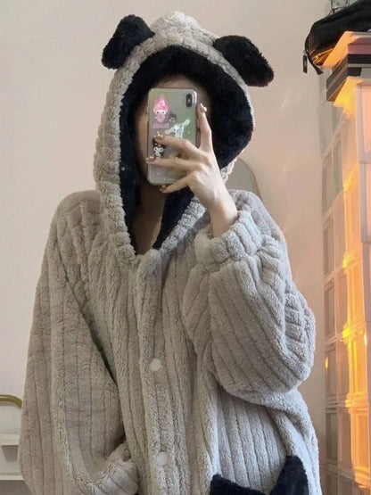 Person in grauem, plüschigem Bären-Overall mit Kapuze und Ohren, Selfie im Spiegel.