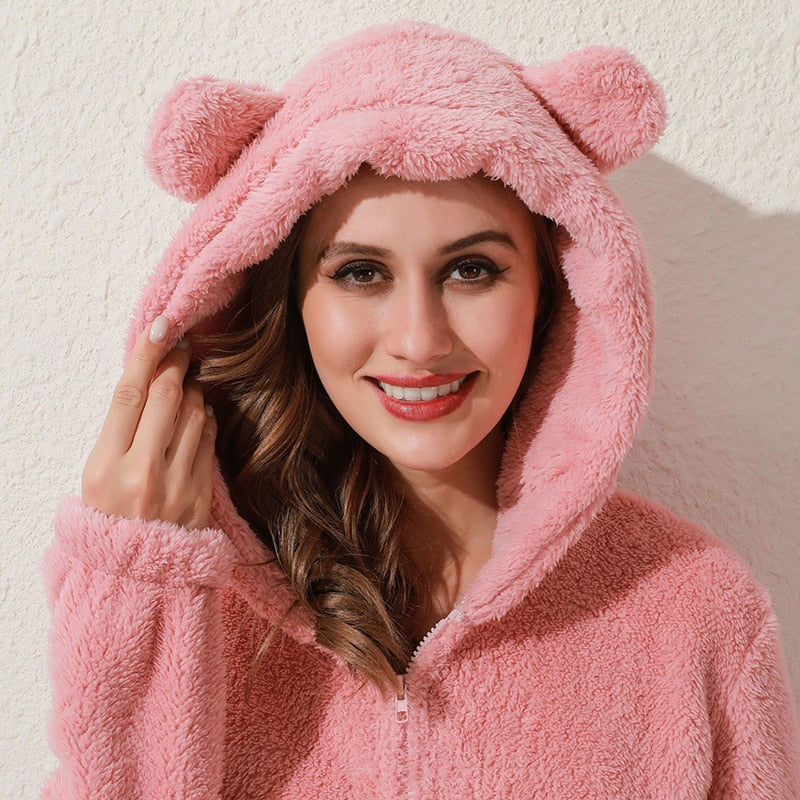 Frau in rosa Plüsch-Kapuzenpullover mit Bärenohren, gemütliche Damenmode, Winterkleidung.