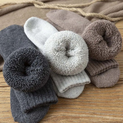 Warme Wollsocken in Grau- und Brauntönen auf Holztisch, gemütliche Winterkleidung.