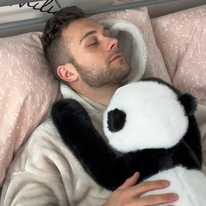 Man sover i sängen med pandan i famnen och dess långa svarta arm över sin axel. 11
