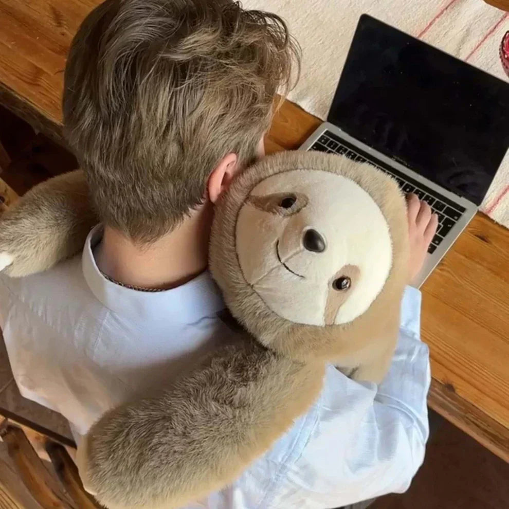 Ovanifrån sedd person vid laptop med ett sengångargosedjur som kramar om axlarna och nacken med långa armar. 9