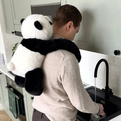 Man står vid diskbänken i köket med pandakramdjuret lindat över axlarna och hängande ner längs ryggen. 10