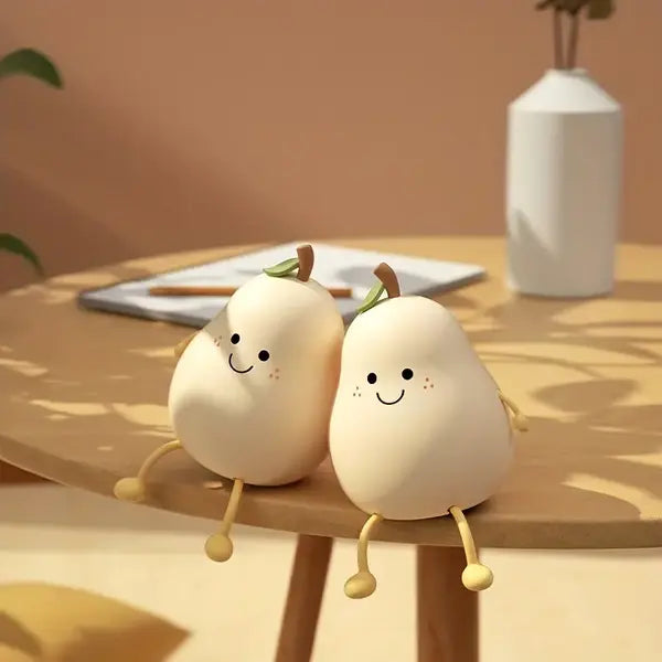 Zwei lächelnde Birnen-Dekorationen aus Keramik auf Holztisch, beige Hintergrund.