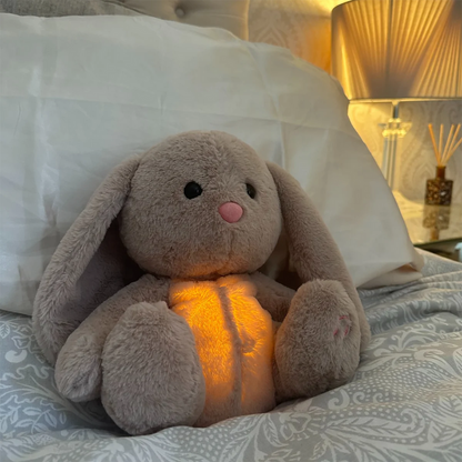 Kuscheltier Hase mit Leuchtfunktion, grau, auf Bett, Nachtlicht, Kinderzimmer-Dekoration.