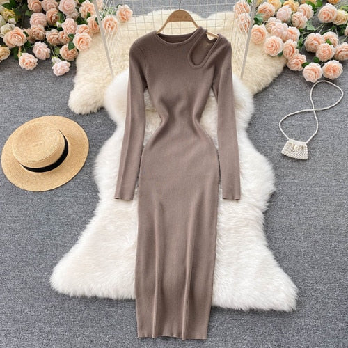 Braunes Strickkleid mit asymmetrischem Ausschnitt, langärmelig, auf weißem Fell, umgeben von Rosen.