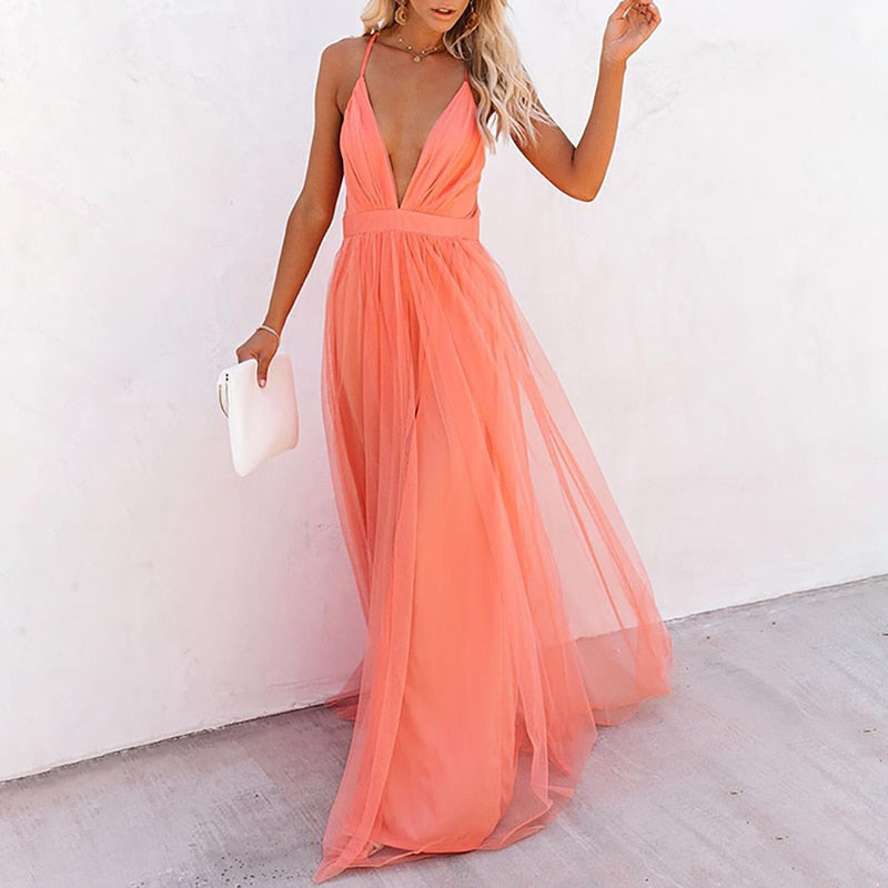Frau im pfirsichfarbenen Abendkleid aus Tüll mit tiefem Ausschnitt, hält weiße Clutch.