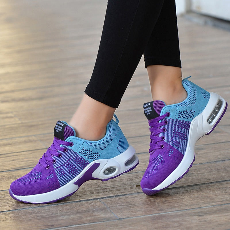 Lila und blaue Damen-Sneaker, atmungsaktiv, mit Luftpolstersohle, auf Holzboden.