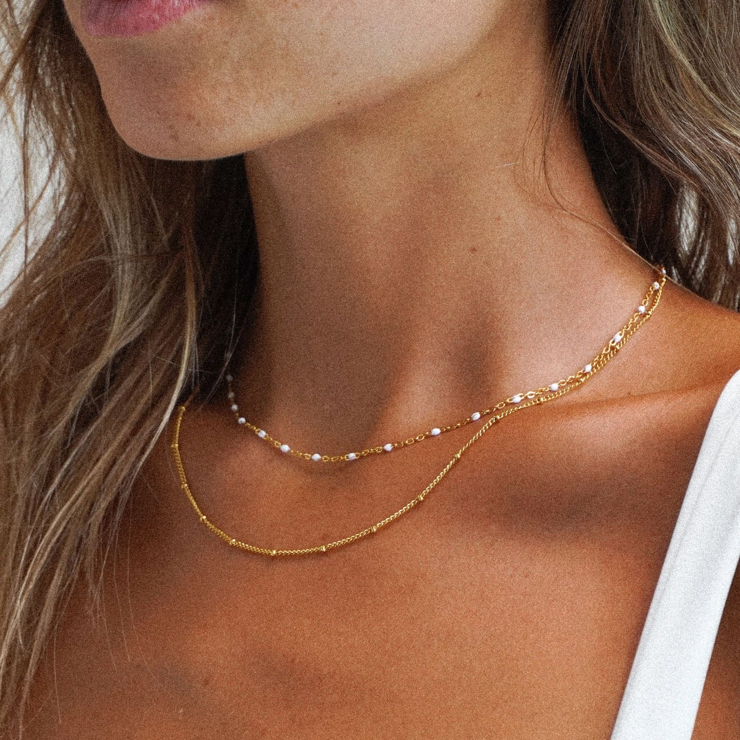 Frau trägt goldene, filigrane Halskette, modisches Schmuckstück, elegantes Design.