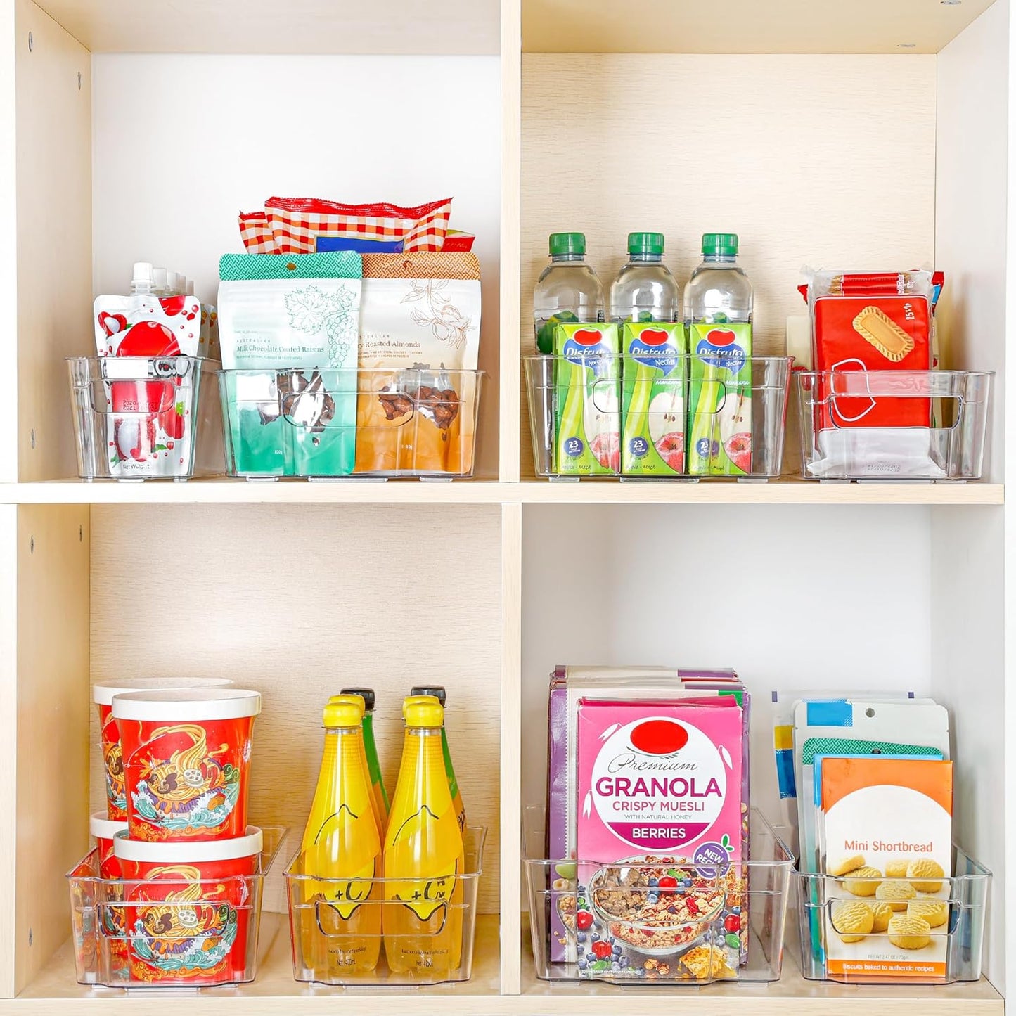 Vorratsschrank mit Getränken, Snacks und Müsli in transparenten Aufbewahrungsboxen.