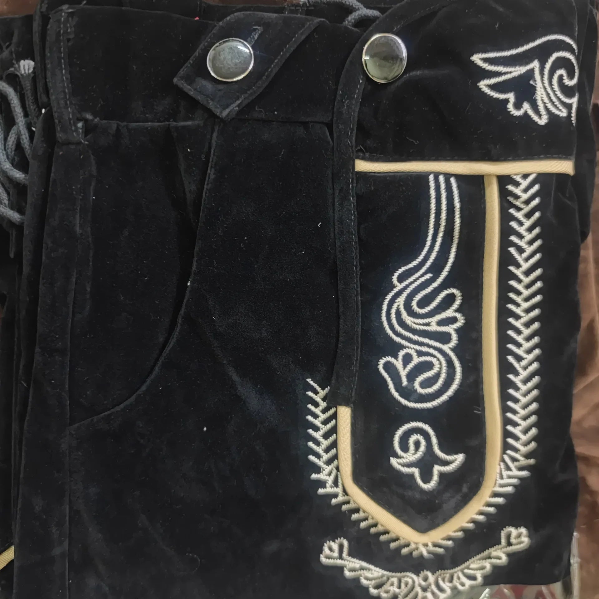 Schwarze Lederhose mit Stickerei, Trachtenmode, traditionell, Knöpfe, Detailansicht.