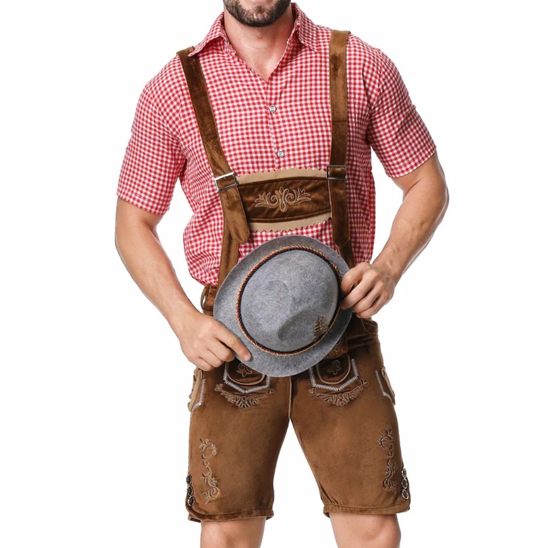 Mann in brauner Lederhose und rotem Karohemd, hält grauen Hut, traditionelle bayerische Tracht.