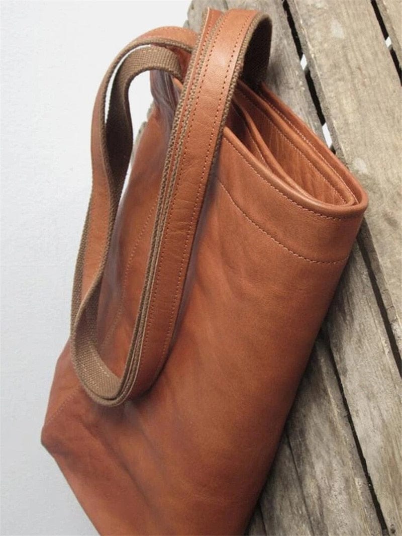 Braune Ledertasche mit robusten Trägern auf Holzhintergrund, langlebige Tragetasche.
