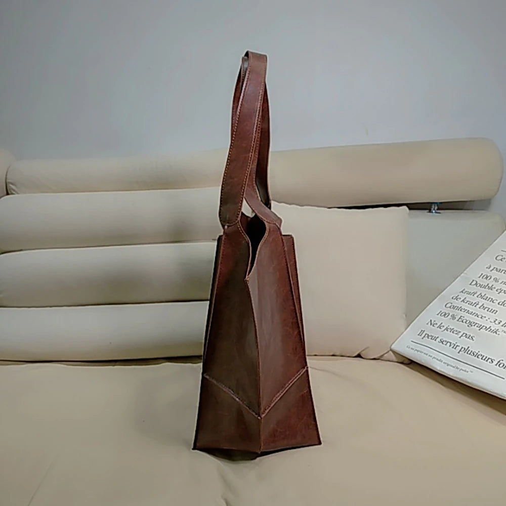 Braune Ledertasche, minimalistisches Design, auf beigem Sofa, stilvolle Handtasche für Damen.