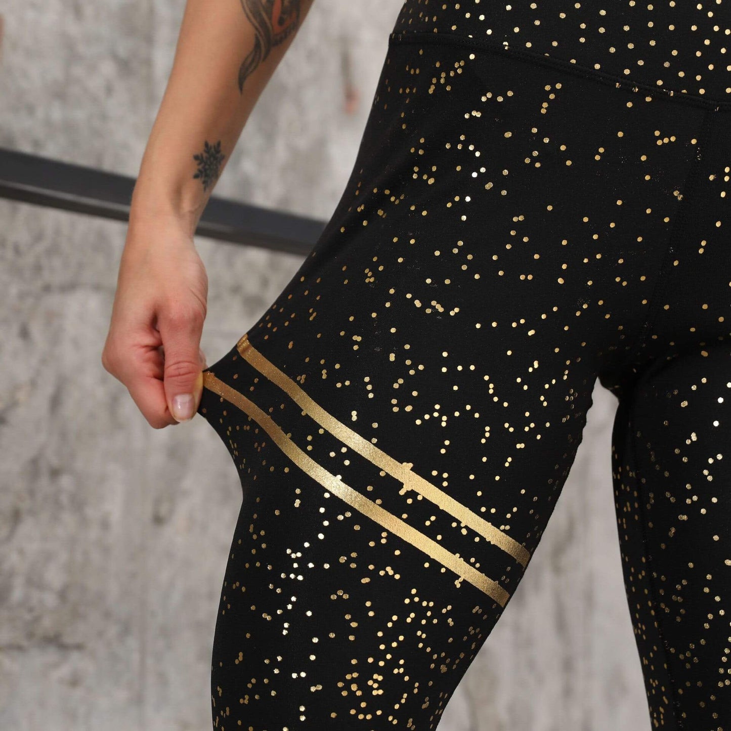 Schwarze Damen-Sportleggings mit goldenen Punkten, elastisch, figurformend, Fitnessmode.