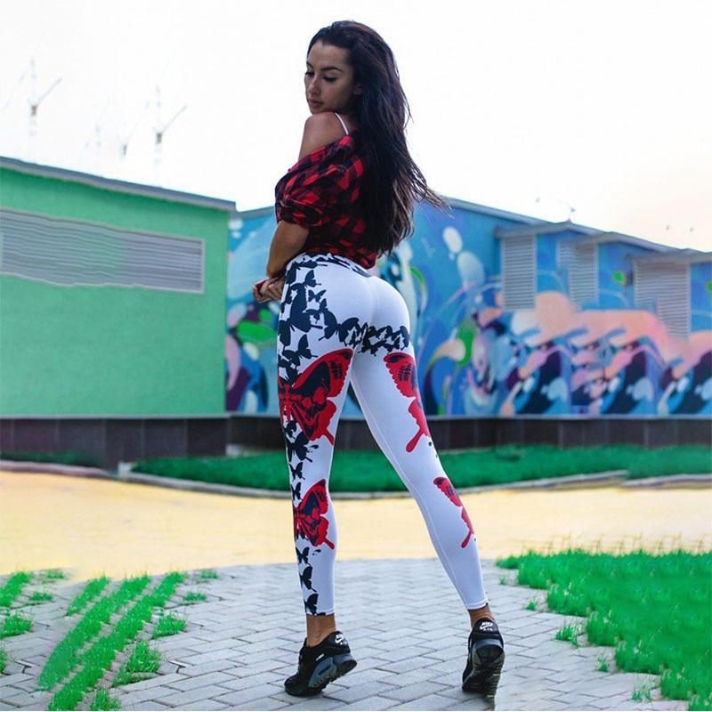 Frau in weißen Leggings mit Schmetterlingsmuster, rotem Oberteil, urbaner Hintergrund.