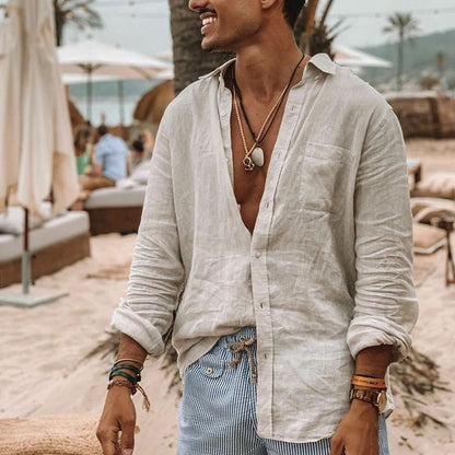 Mann am Strand in weißem Leinenhemd, gestreifter Hose, Schmuck; Sommermode, Herrenbekleidung.