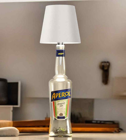 Lampa med vit skärm på en genomskinlig flaska, placerad på en köksbänk i en ljus miljö. 3