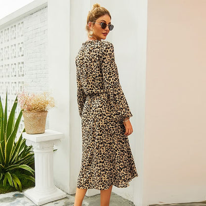 Frau in langem, gepunktetem Leopardenkleid, Sonnenbrille, draußen, modisch, elegant.