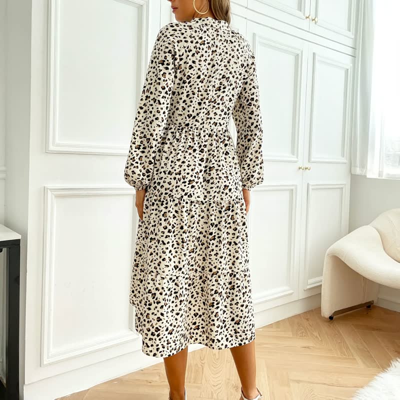 Frau in langem, weißem Kleid mit schwarzem Leopardenmuster, stehend in modernem Raum.