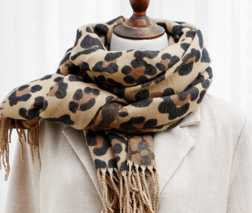 Leopardenmuster Schal aus Wolle, beige und braun, auf beigem Mantel drapiert.