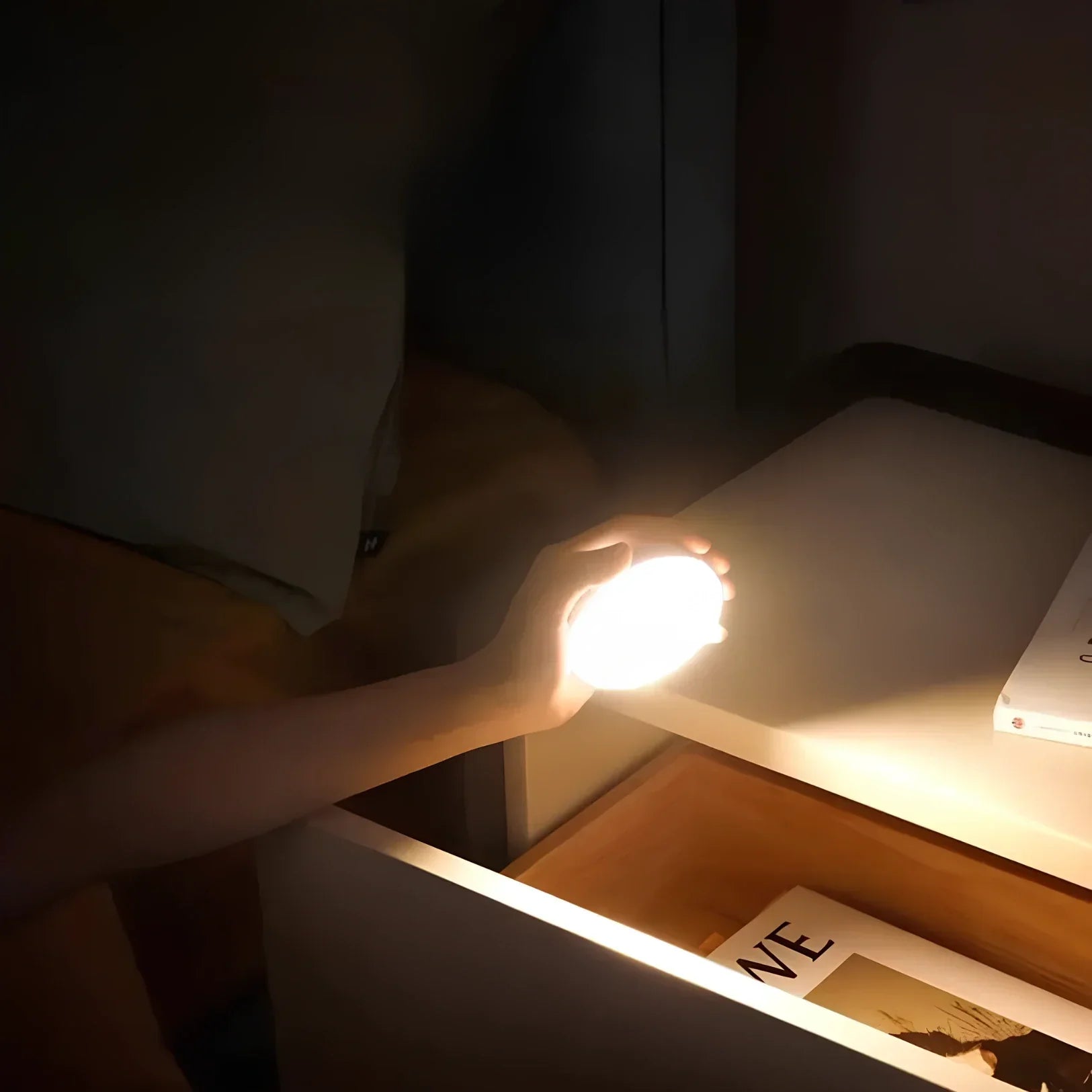 Hand hält leuchtende LED-Lampe am Nachttisch, modernes Design, warmes Licht, Schlafzimmerbeleuchtung.