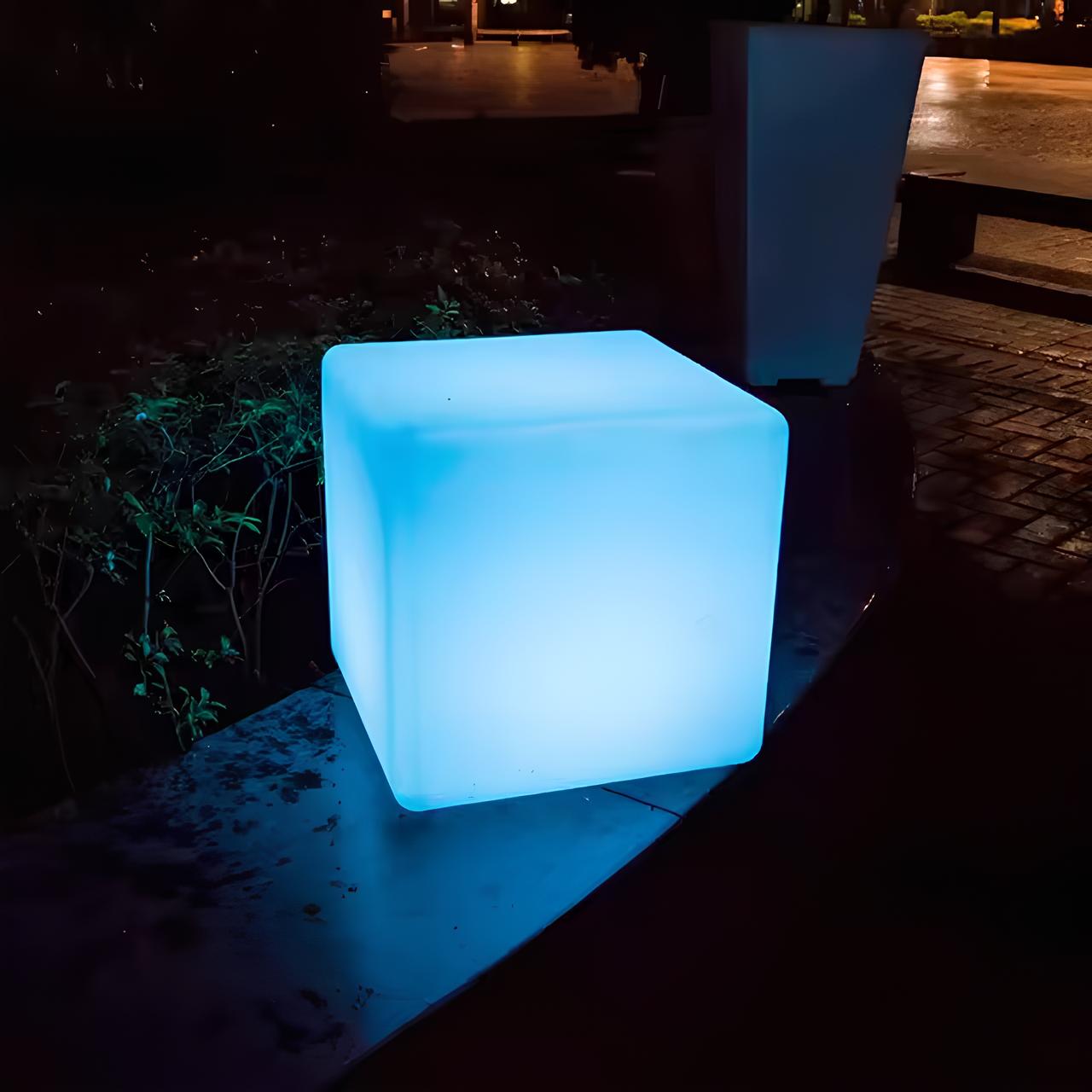 Leuchtender blauer LED-Würfel im Freien, moderne Gartenbeleuchtung, Nachtaufnahme.
