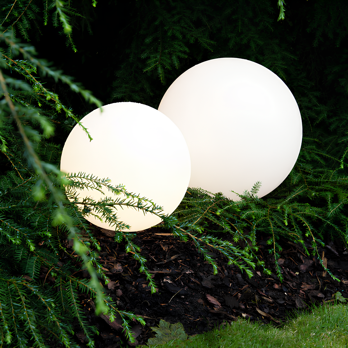 Zwei leuchtende Gartenkugeln, weiß, LED, dekorative Außenbeleuchtung, im Grünen platziert.