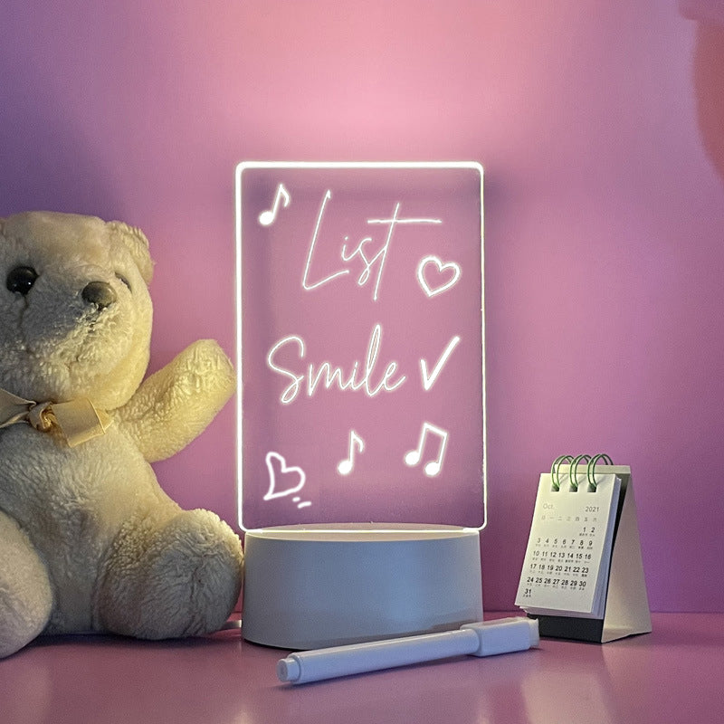 Teddybär und LED-Nachtlicht mit Schriftzug "Smile" auf rosa Hintergrund, Tischkalender daneben.