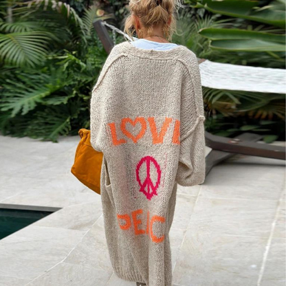 Frau in beiger Strickweste mit "Love" und "Peace" Aufdruck, Hippie-Stil, Gartenhintergrund.