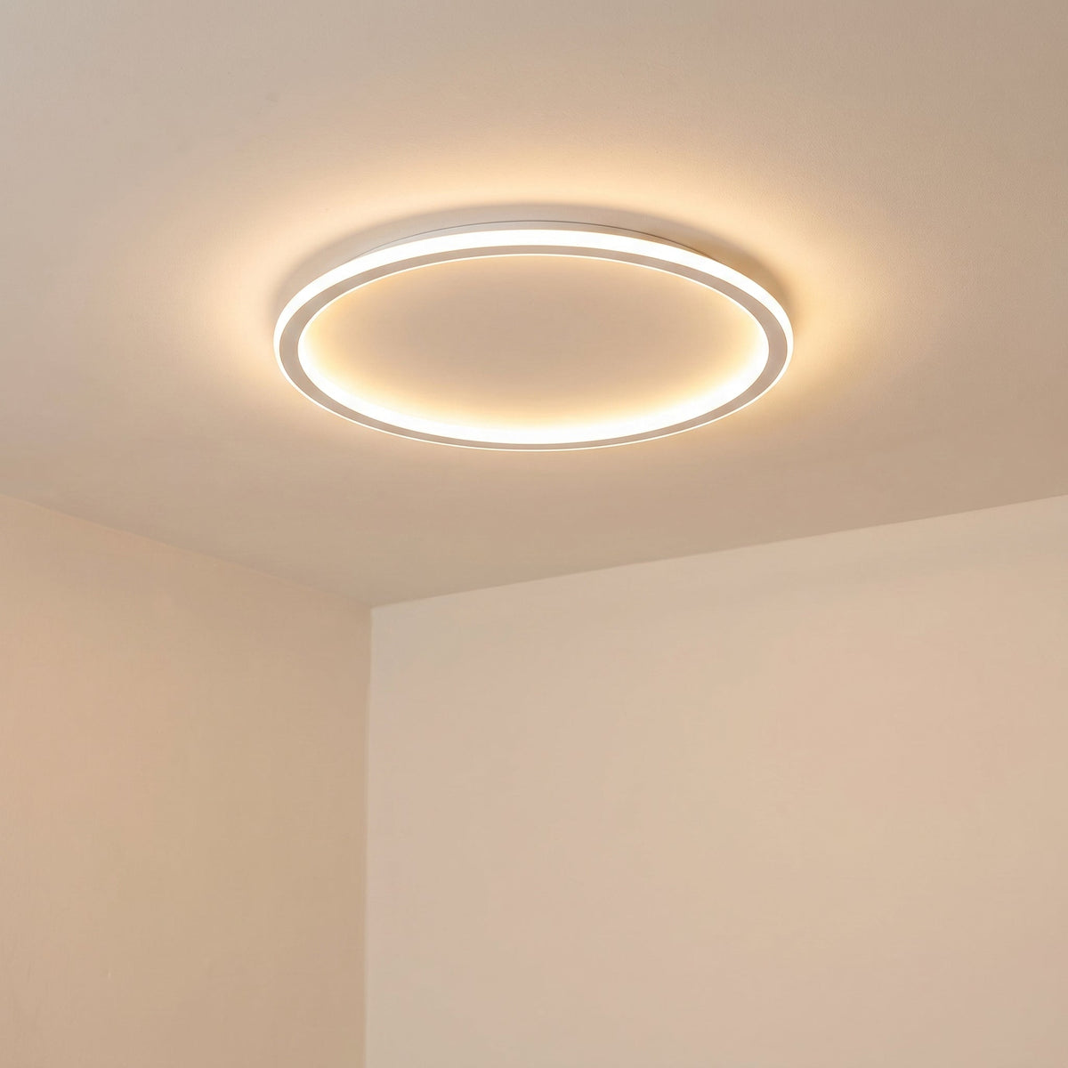 Tänd vit ringlampa sedd snett underifrån mot ett takhörn, med mjukt varmt ljus som sprids över taket. 6