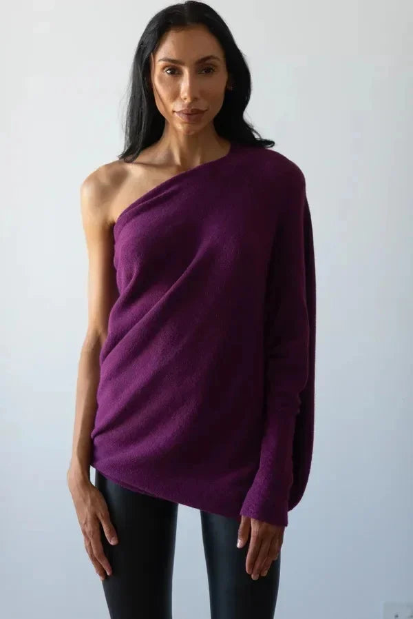 Frau in lila, schulterfreiem Pullover, schwarze Leggings, Mode, eleganter Look.