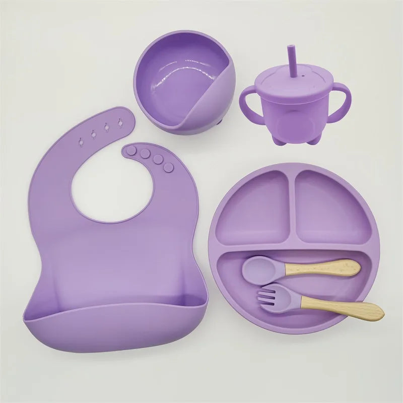 Lila Silikon-Babygeschirr-Set mit Lätzchen, Teller, Becher, Schüssel und Besteck.