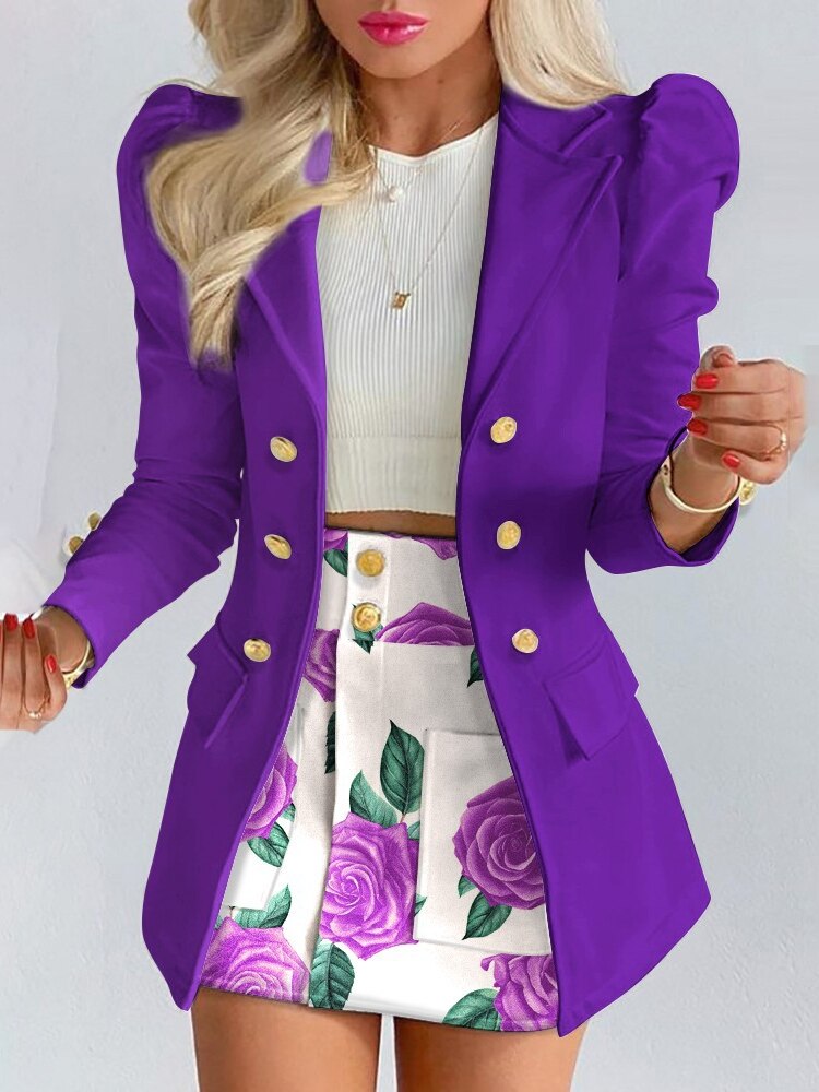 Frau in lila Blazer mit goldenen Knöpfen, weißem Top und floralem Rock, modisch, elegant.