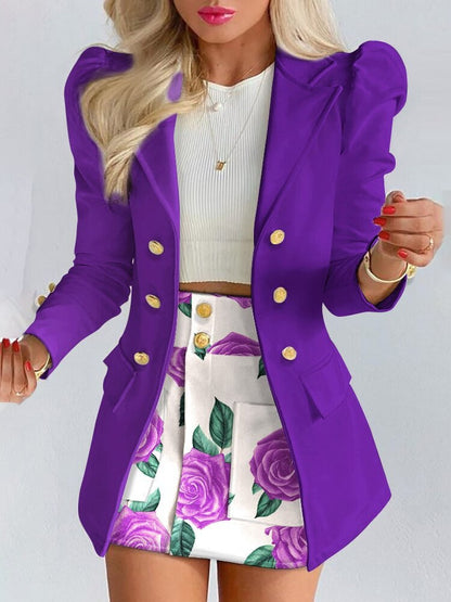Frau in lila Blazer mit goldenen Knöpfen, weißem Top und floralem Rock, modisch, elegant.