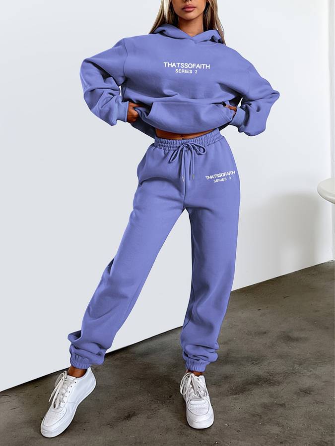 Frau in lila Jogginganzug mit Kapuze und weißen Sneakers, lässige Mode, Sportbekleidung.