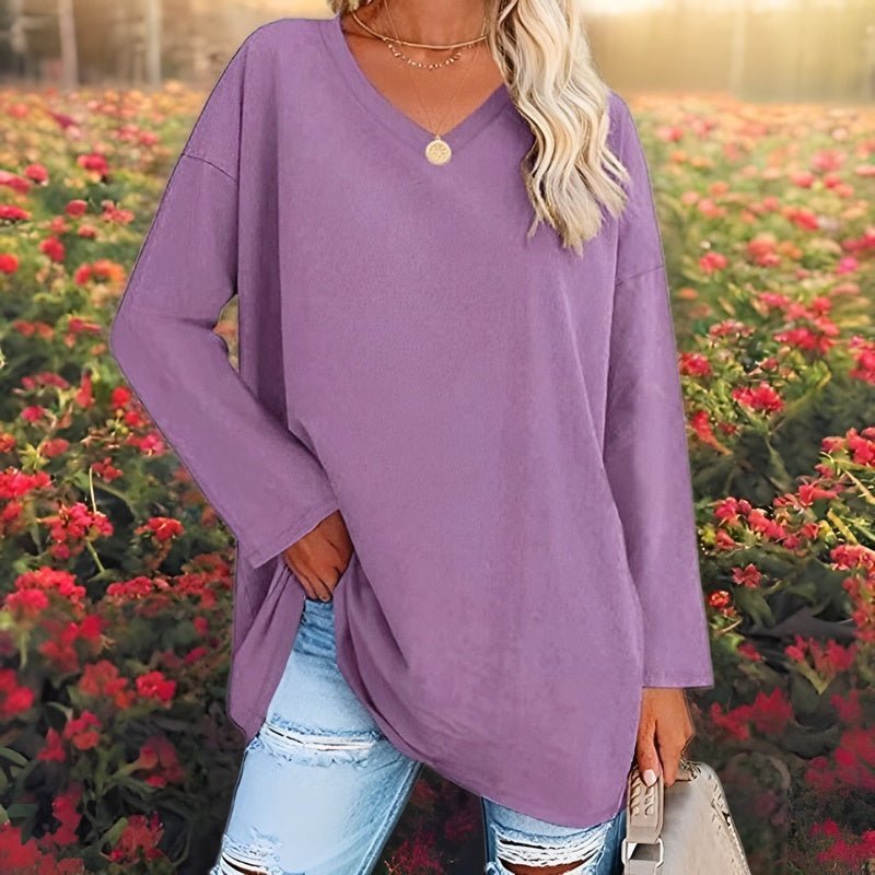 Frau in lila Pullover, zerrissene Jeans, Blumenfeld, modisch, lässig, Herbstmode.