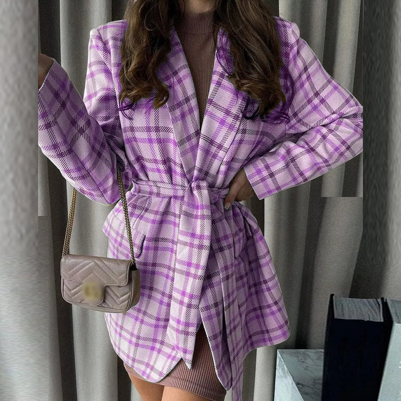 Frau in lila kariertem Blazer-Kleid mit Gürtel, braune Umhängetasche, modisch, elegant.