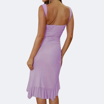 Frau in lila ärmellosem Kleid, knielang, figurbetont, mit Rüschen, elegantes Abendoutfit.