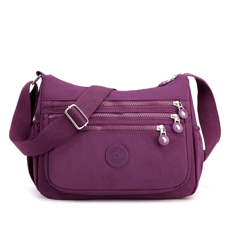Lila Umhängetasche mit Reißverschlüssen, verstellbarem Gurt, ideal für Damen, modisch und praktisch.