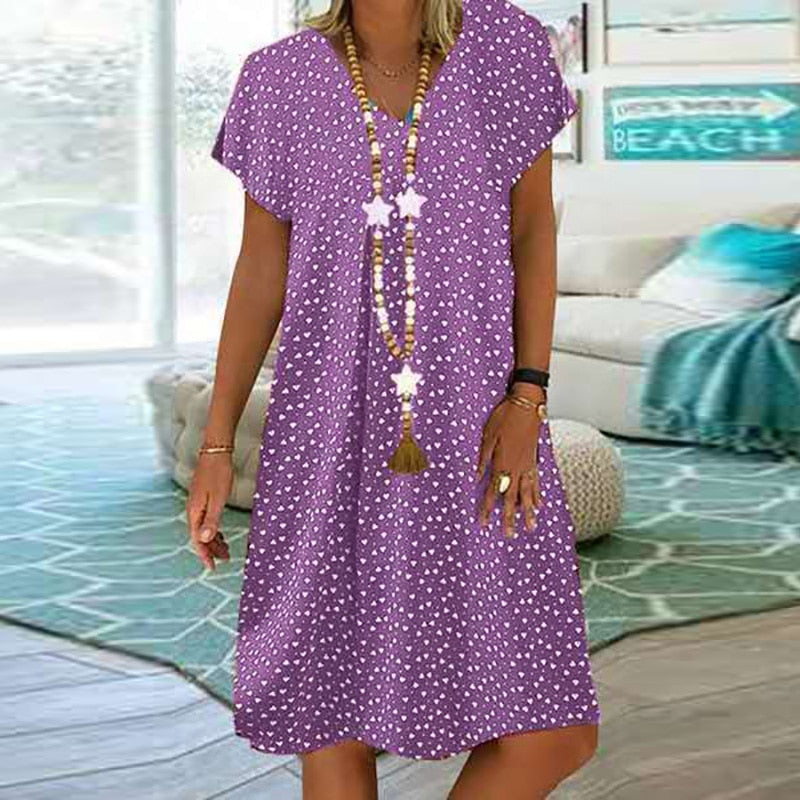 Frau in lila Sommerkleid mit weißen Punkten, lässig, Strandhaus-Hintergrund.