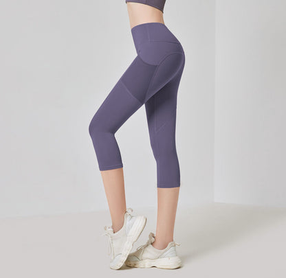 Frau in lila Sportleggings, knielang, mit weißen Turnschuhen, Fitnessmode, seitliche Ansicht.