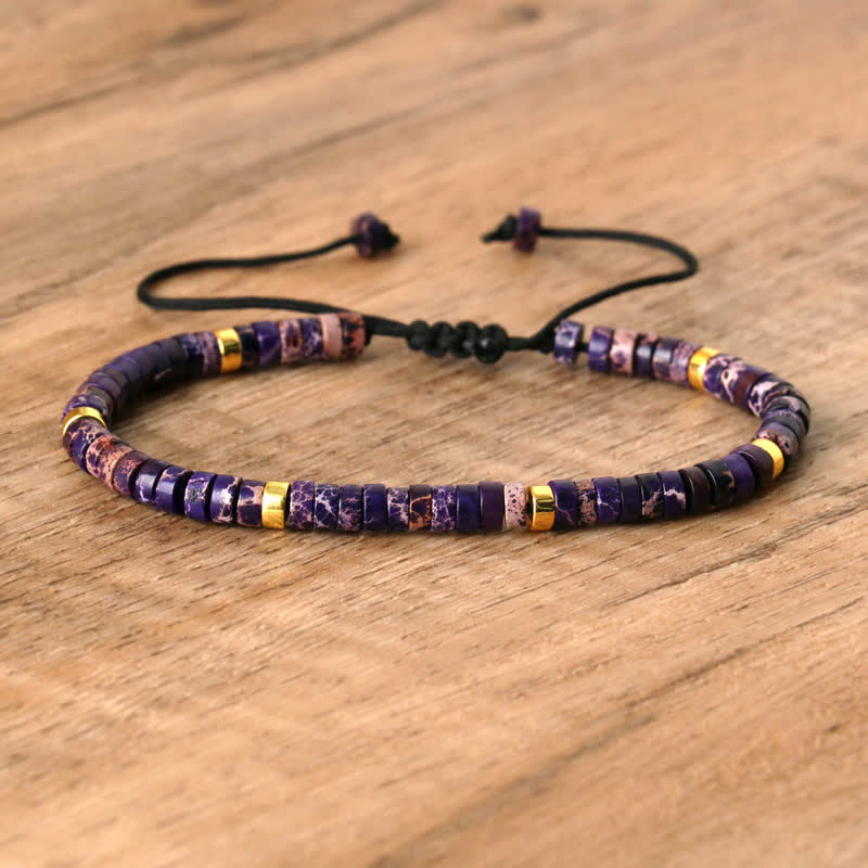 Lila Armband mit goldenen Akzenten, verstellbar, handgefertigt, Schmuck auf Holzoberfläche.