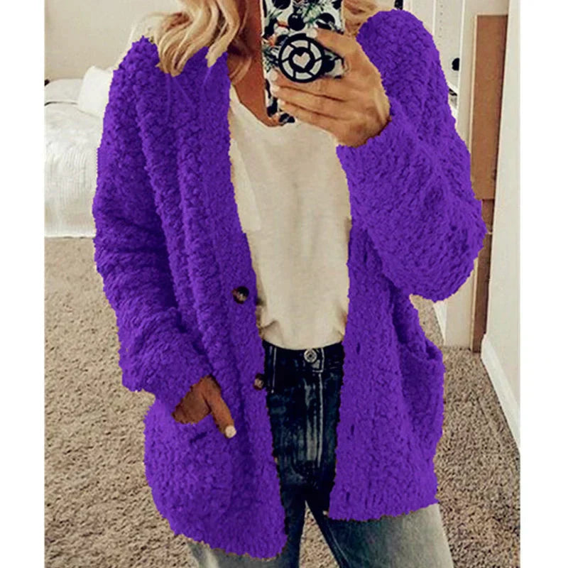 Frau in lila Strickjacke, weißem T-Shirt und Jeans, Selfie im Schlafzimmer.
