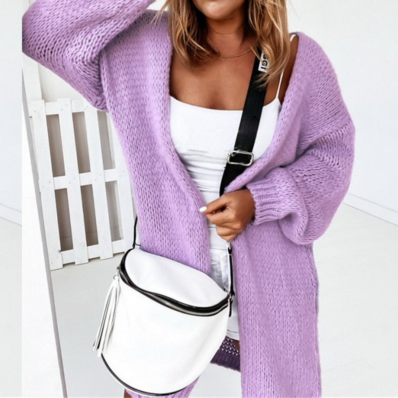 Frau in lila Strickjacke mit weißer Umhängetasche, modisch, lässig, Damenmode.
