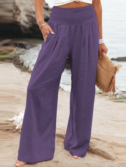 Frau in lila Leinenhose am Strand, Sommermode, lässig, bequem, Damenbekleidung.
